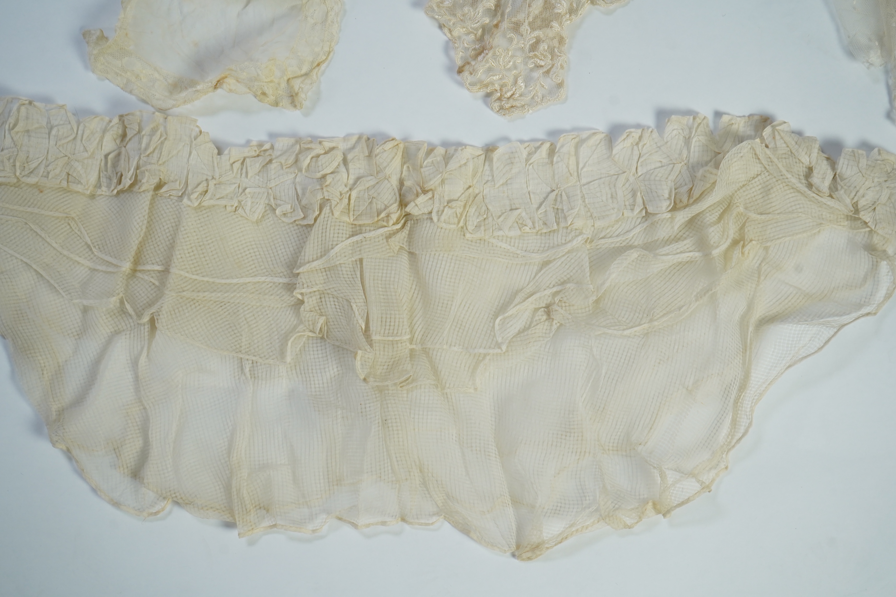 A suitcase containing a cream silk lace skirt to a dress, an Edwardian silk petticoat and various collars, possibly for theatrical use, silk petticoat 96 cm long. Condition - fair